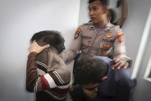 Police officer escorts two men accused of having gay sex into a holding cell to wait for the start of their trial at Shariah court in Banda Aceh, Indonesia, Wednesday, May 17, 2017.