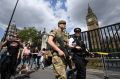 An armed soldier and a police officer patrol outside the Houses of Parliament in London.