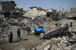 File - Residents carry the body of several people killed during fights between Iraq security forces and Islamic State on the western side of Mosul, Iraq, Friday, March 24, 2017.