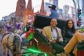 People on a horse drawn carriage between Flinders Street Station and Federation Square.