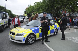 Armed police watch Courteeners' fans arrive for a concert at Old Trafford cricket ground in Manchester, England, Saturday, May 27 2017.