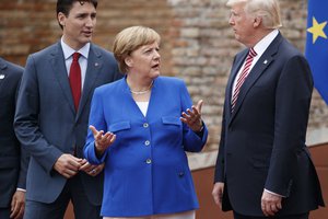 German Chancellor Angela Merkel, center, talks with Canadian Prime Minister Justin Trudeau, left, and President Donald Trump during a family photo with G7 leaders at the Ancient Greek Theater of Taormina during the G7 Summit, Friday, May 26, 2017, in Taormina, Italy.