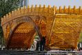 Workers install wires on a 'Golden Bridge of Silk Road' structure on a platform outside the National Convention Centre ...