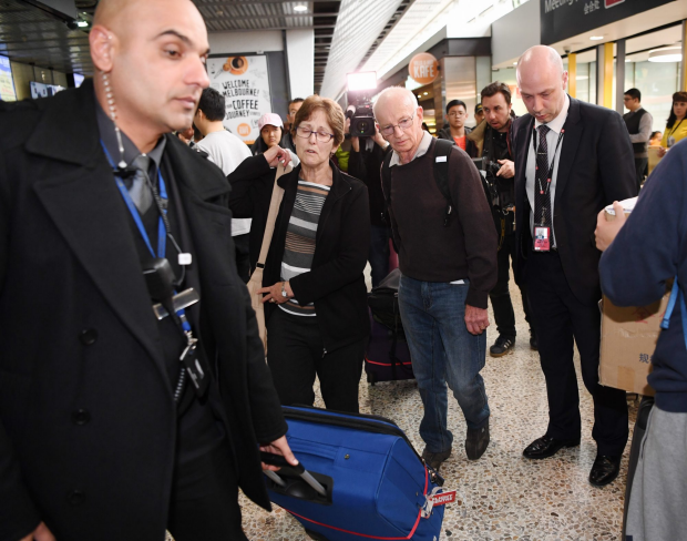 Pam and Stan Young are escorted from the airport by security.