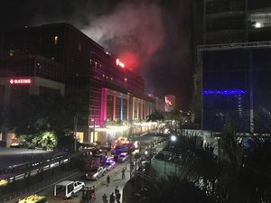 Emergency responders and security officials are parked outside as smoke rises from the Resorts World Manila complex, early Friday, June 2, 2017, in Manila, Philippines