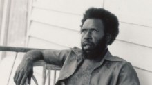 A black and white photo of a man reclining on a chair.