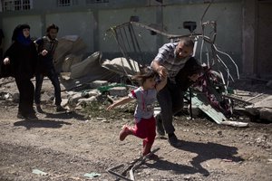 A man rushes his daughter to safety while fleeing the al-Refai neighborhood as Iraqi special forces battle Islamic State militants in western Mosul, Iraq, Wednesday, May 17, 2017.(AP Photo/Maya Alleruzzo)