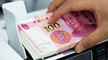 An employee places Chinese one-hundred yuan banknotes into a counting machine at the Counterfeit Notes Response Center ...