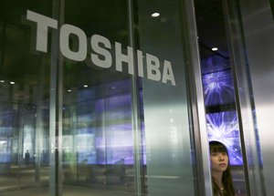 A woman walks past the Logo of Toshiba in Kawasaki near Tokyo, Friday, Jan. 27, 2017.