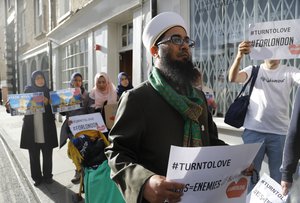 Chairman of the London Fatwa Council, Mohammad Yazdani Raza hold a sign as he marches near Borough Market in London, Sunday, June 4, 2017.