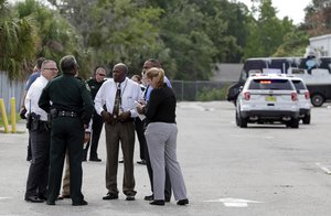 Authorities confer near the scene of a shooting where they said there were multiple fatalities in an industrial area near Orlando, Fla., Monday, June 5, 2017.