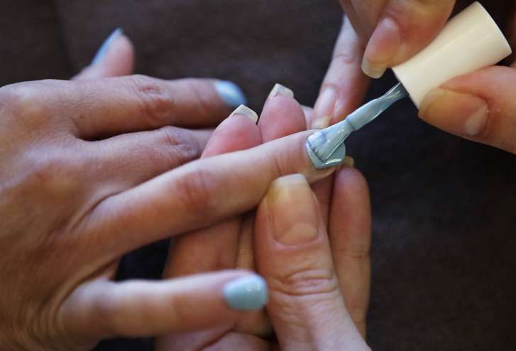 In this Tuesday, Aug. 23, 2016, photo, Christine Perkins, right, who owns Pyara Spa and Salons at two locations in the Boston area, applies nail polish for a client at her salon in Burlington, Mass. Perkins struggles to find candidates to style hair, do manicures and give massages, in part because some beauty schools in the region have closed. (AP Photo/Charles Krupa)