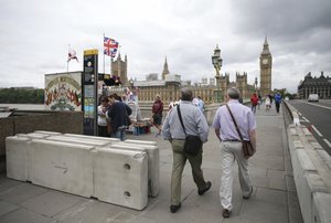 Pedestrians walk through newly installed barriers on Westminster Bridge in London, Monday, June 5, 2017.