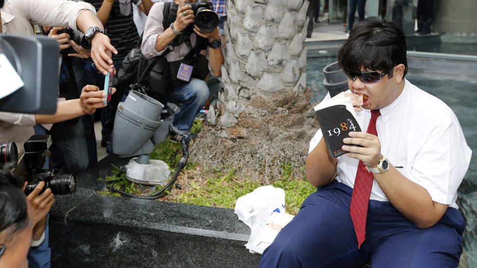 Man reading 1984 in Thailand, being documented by cellphones.