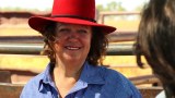 Gina Rinehart smiles while standing in front of cattle pens