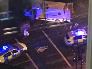 Police surround the van used by the attackers at London Bridge, Saturday June 3, 2017. The assault began Saturday night when a van veered off the road and barreled into pedestrians on busy London Bridge. Three men fled the van with large knives and attacked people at bars and restaurants in nearby Borough Market, police and witnesses said. (AP Photo/Kevin Dunne)