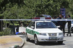 The body at background left, lies on the ground while police control the scene at the shrine of late Iranian revolutionary founder Ayatollah Khomeini, just outside Tehran, Iran, Wednesday, June 7, 2017. Suicide bombers and gunmen stormed into Iran's parliament and targeted the shrine of Ayatollah Ruhollah Khomeini on Wednesday, killing a security guard and wounding 12 other people in rare twin attacks, with the siege at the legislature still underway. (AP Photo/Ebrahim Noroozi)