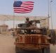A US-backed anti-government Syrian fighter stands on a vehicle next to an American soldier who also stands on his ...