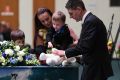 Senior Constable Brett Forte's children Sam, Emma and Brodie place a teddy bear and other items on his casket during his ...