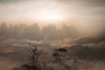 Dawn broke over hundreds of oddly shaped karst mountains bathed in fog on a spring morning.  The town that lies beneath ...