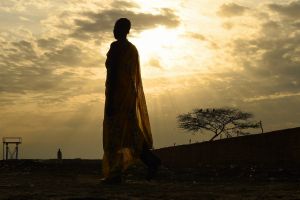 A woman wearing gumboots walks along a path inside the UN Bentiu Protection of Civilian's (POC) site where over 100,000 ...