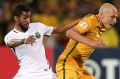 Salman Alfaraj of Saudi Arabia tackles Socceroo Aaron Mooy.