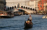 Boats and gondolas pass under the famed Rialto Bridge, seen in the background. 