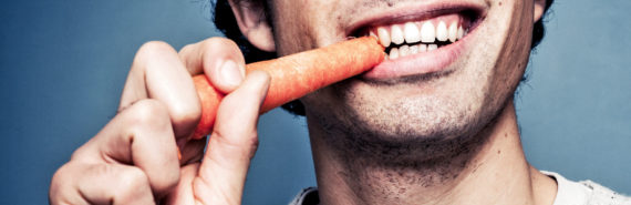 guy smiles while eating carrot