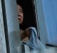 A person peers out of a window from a building on fire in London, Wednesday, June 14, 2017. Metropolitan Police in ...