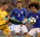 Under pressure: Socceroo James Troisi tries to get a kick away from Brazil’s David Luiz.