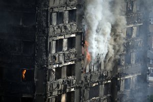 Parts of the building still burn hours after a deadly blaze at a high rise apartment block in London, Wednesday, June 14, 2017.