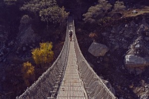 Trekkers crossing wire rope suspension bridge over Kali Gandaki river at Ghasa on Annapurna circuit Himalayas Nepal.