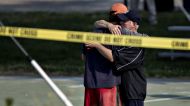 Two people hug in front of police crime scene tape following a shooting during a congressional baseball practice hug ...