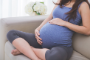 close up portrait of a pregnant stomach sitting on a couch