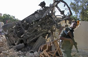 A Somali soldier stands near the wreckage from a car bomb blast and gun battle targeting a restaurant in Mogadishu, Somalia, Thursday, June 15, 2017. S