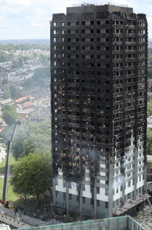 Firefighters inspect the blackened exterior of Grenfell Tower.