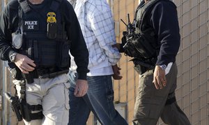 In this March 30, 2012 photo, Immigration and Customs Enforcement (ICE) agents take a suspect into custody as part of a nationwide immigration sweep in Chula Vista, Calif.