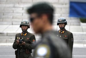 FILE - in this April 17, 2017, file photo, two North Korean soldiers look at the south side as a South Korean soldier, center, stand guard while U.S. Vice President Mike Pence visited the border village of Panmunjom which has separated the two Koreas since the Korean War, South Korea. South Korea’s military on Tuesday, June 13, 2017, said a North Korean soldier walked across the heavily mined border between the countries and defected to the South. The Joint Chiefs of Staff said in a statement that the soldier was being questioned about the reasons for his defection. (AP Photo/Lee Jin-man, File)