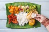 Indian woman eating banana leaf rice, overhead view on wooden dining table. SatJun17cover-WorldFood - Ben Groundwater ...