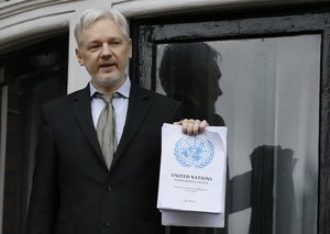 Wikileaks founder Julian Assange holding the UN report speaks on the balcony of the Ecuadorean Embassy in London, Friday, Feb. 5, 2016.