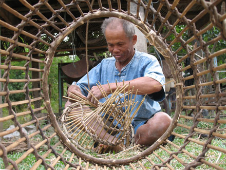 Pan Maneepak works on the interior of a fish trap in Tha Sala Village, Thailand. 