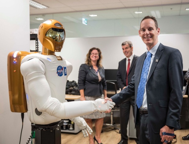 Woodside Energy chief technology officer Shaun Gregory shakes the Robonaut's hand at Woodside's Perth office.