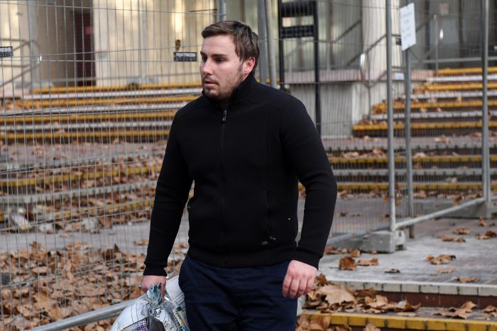 Adam Cranston leaving the Sydney Police Centre in Surry Hills, wearing all black and carrying papers in his right hand