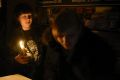 Street side cafe employees light a candle, after a power failure, in Simferopol, Crimea, Sunday, Nov. 22, 2015. Russia's ...