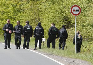 German police officers search for evidence in a forest near Oberursel, Germany, Thursday, April 30, 2015.  Police arrested suspects there earlier the day.(AP Photo/Michael Probst)