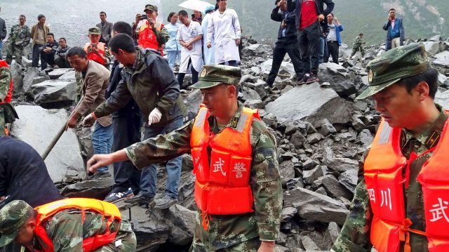 Emergency personnel and local people work at the site of a landslide in Xinmo village in Maoxian County in southwestern ...