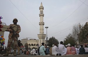 A Pakistani paramilitary soldier stands guard while Muslims attend the Eid al-Fitr prayer, that marks the end of the Muslim holy month of Ramadan, in Karachi, Pakistan, Monday, June 26, 2017.