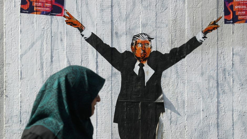 BERLIN, GERMANY - JUNE 27: A Muslim woman walks past a street artist's rendition of U.S. President Donald Trump on June ...