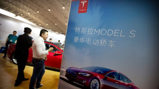 Visitors look at a Tesla Model S electric car on display at the Beijing International Automotive Exhibition in Beijing ...