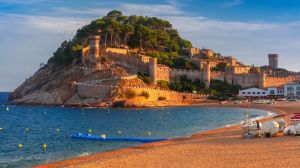 Fortress and fishing boats at Gran Platja beach and Badia de Tossa bay in the evening in Tossa de Mar on Costa Brava, ...